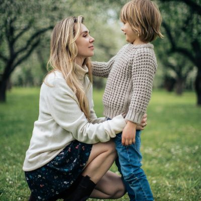 A mother and son share a tender moment in a verdant park during the day.